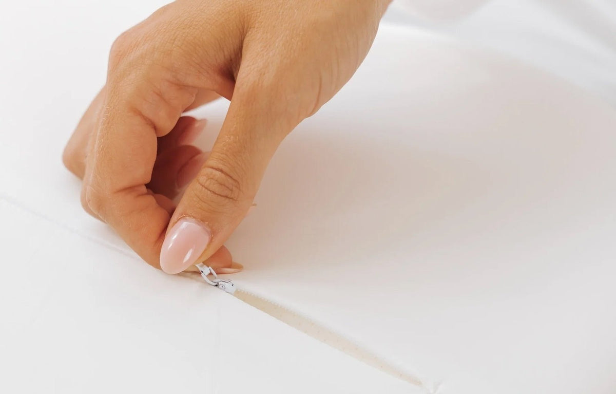 Hand unzipping the removable cover of the ergonomic pillow