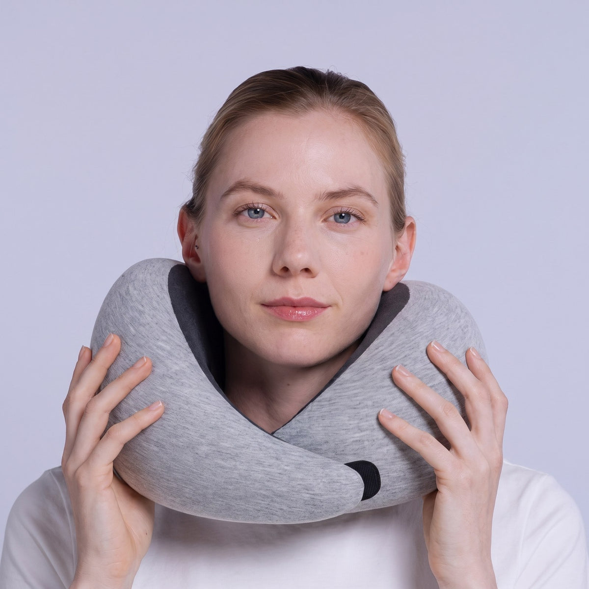 Woman holding the gray travel neck pillow around her neck